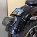 A laydown license plate mount attached to the rear fender of a motorcycle, displaying a license plate.
