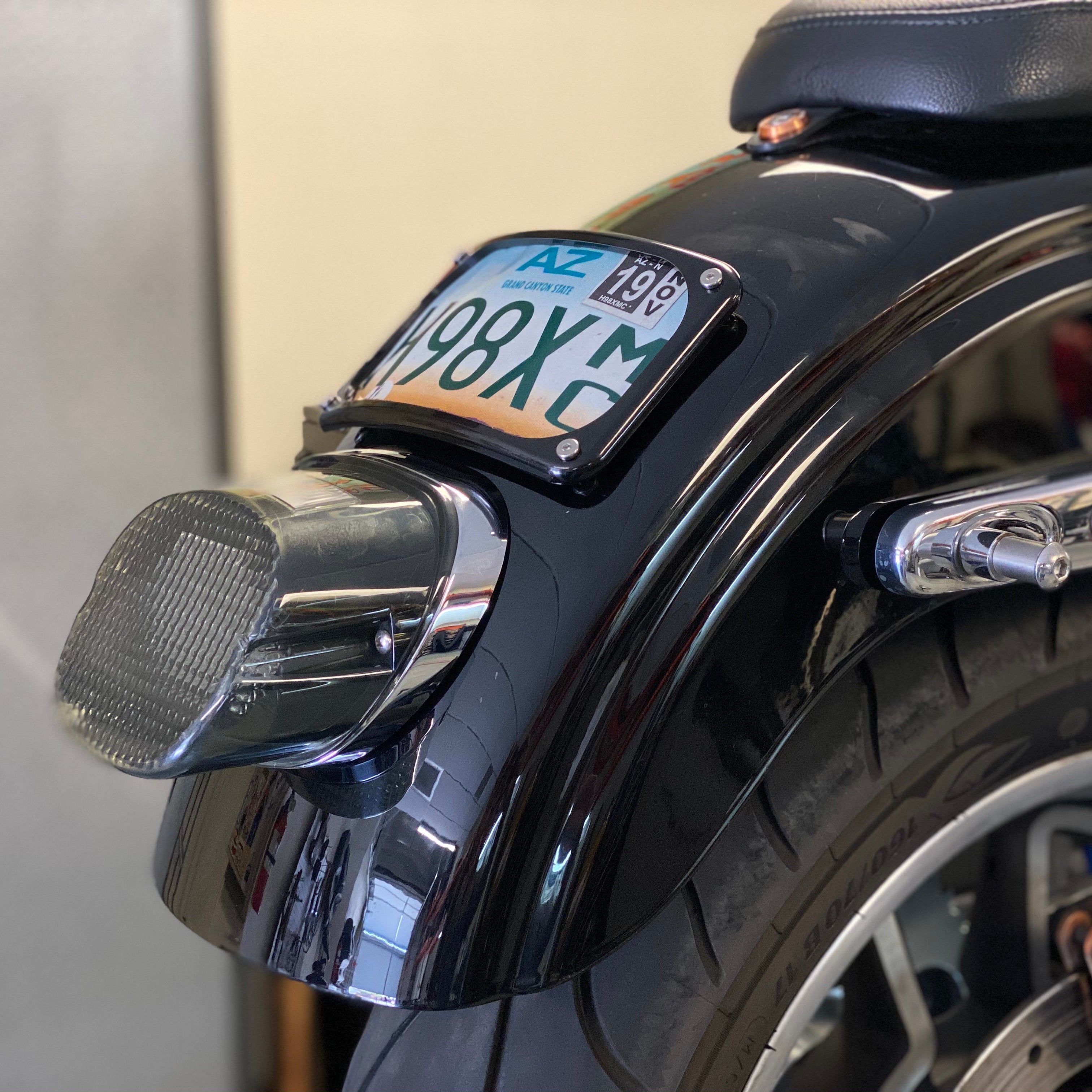 A laydown license plate mount attached to the rear fender of a motorcycle, displaying a license plate.